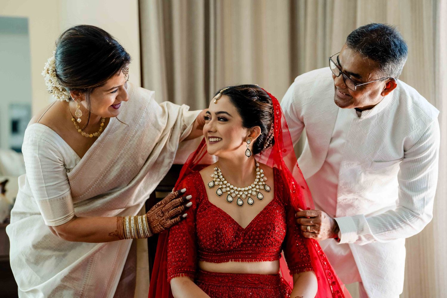 Intimate moment during traditional Indian wedding preparations with beautiful red bridal attire.