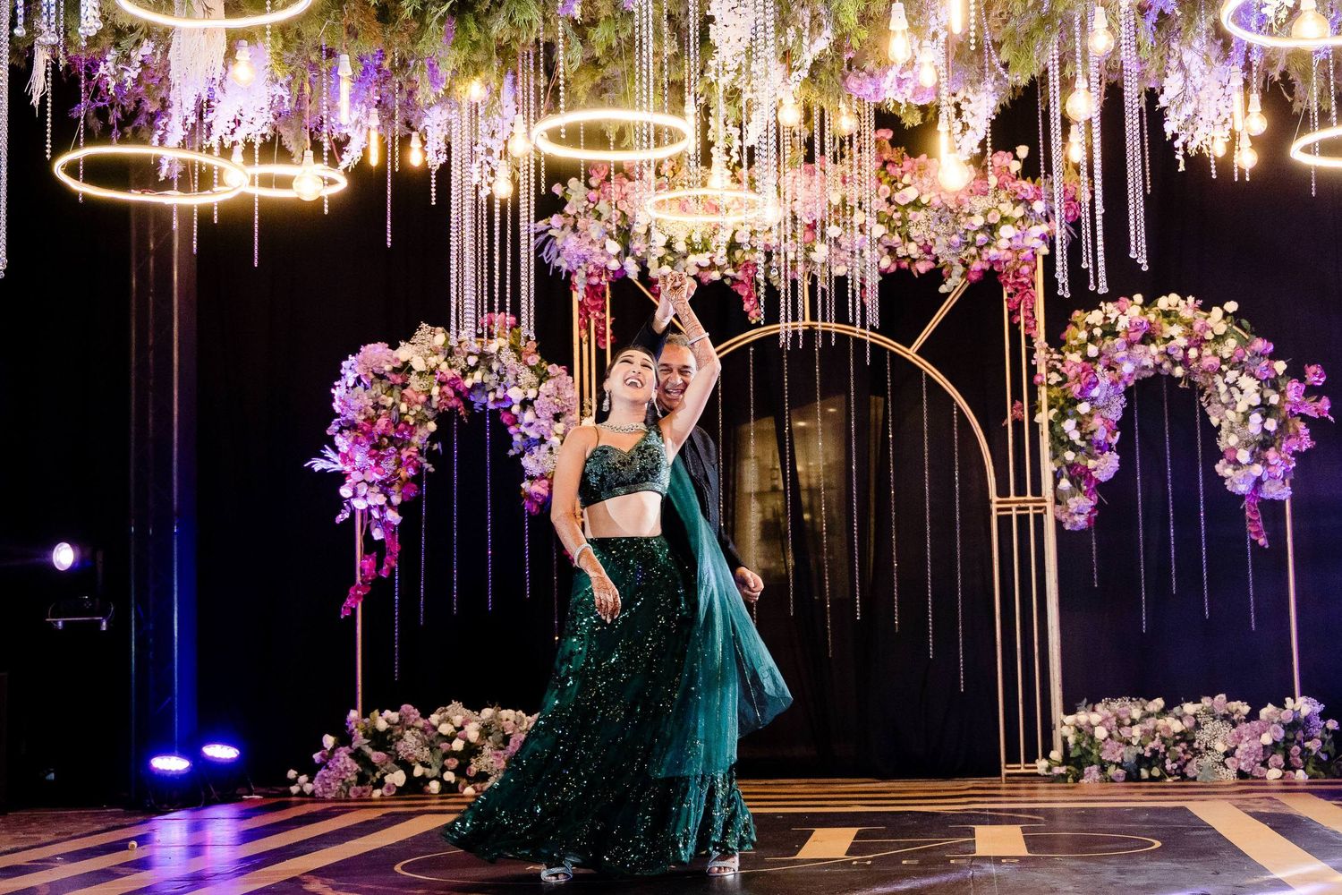 Elegant ballroom decorated with hanging wisteria flowers and circular arches for a luxurious evening celebration.