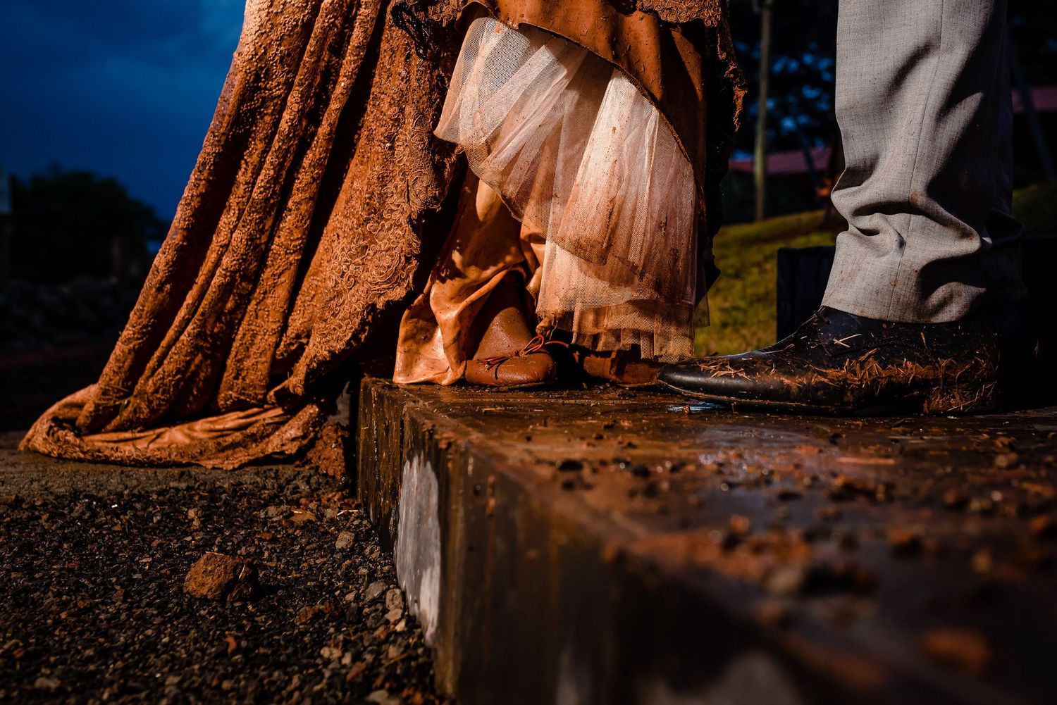 Artistic detail shot of formal shoes and dress hem on concrete step at dusk.