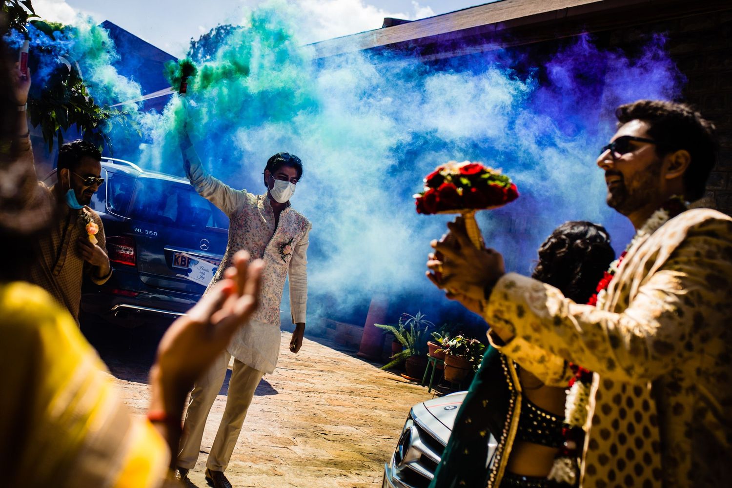Celebratory moment with colorful smoke bombs creating vibrant blue and turquoise atmosphere at outdoor event.