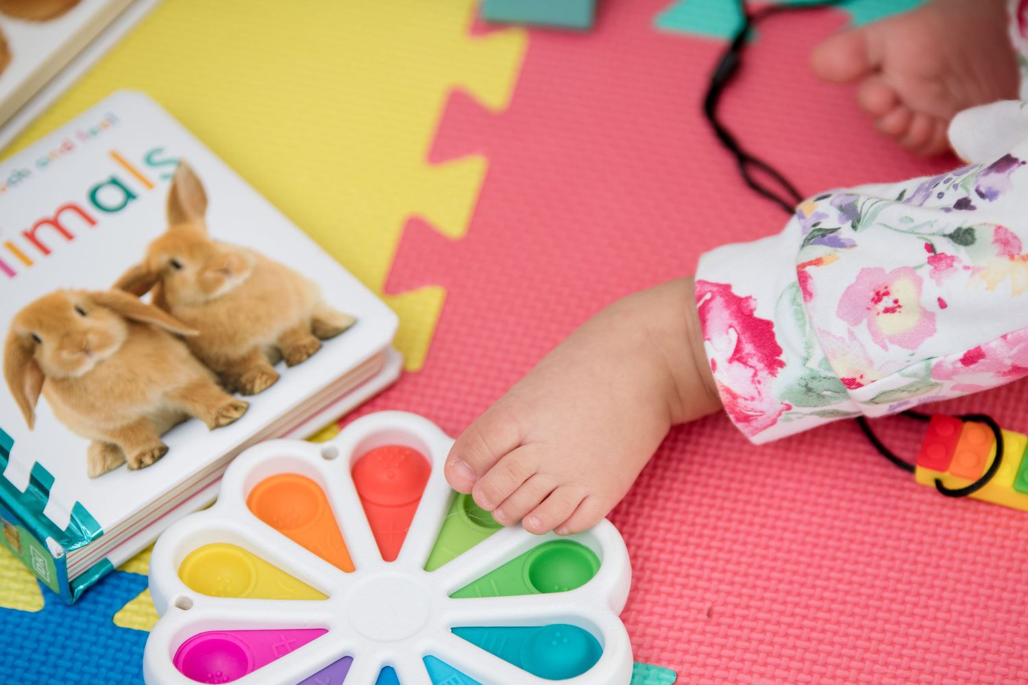 Children work on colorful arts and crafts projects with paper cutouts and supplies on a bright pink table surface.