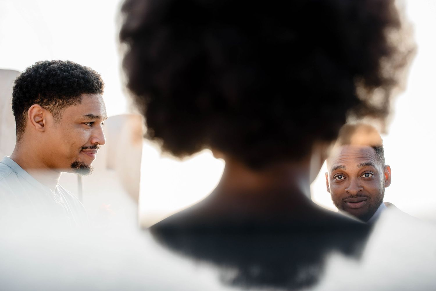 Three people engaged in an intimate conversation with selective focus on their profiles and expressions.