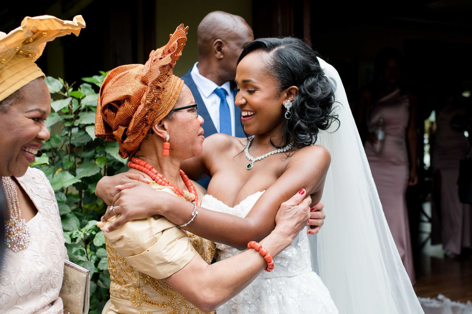 Emotional moment captured at a wedding as guests in bright attire share embraces.