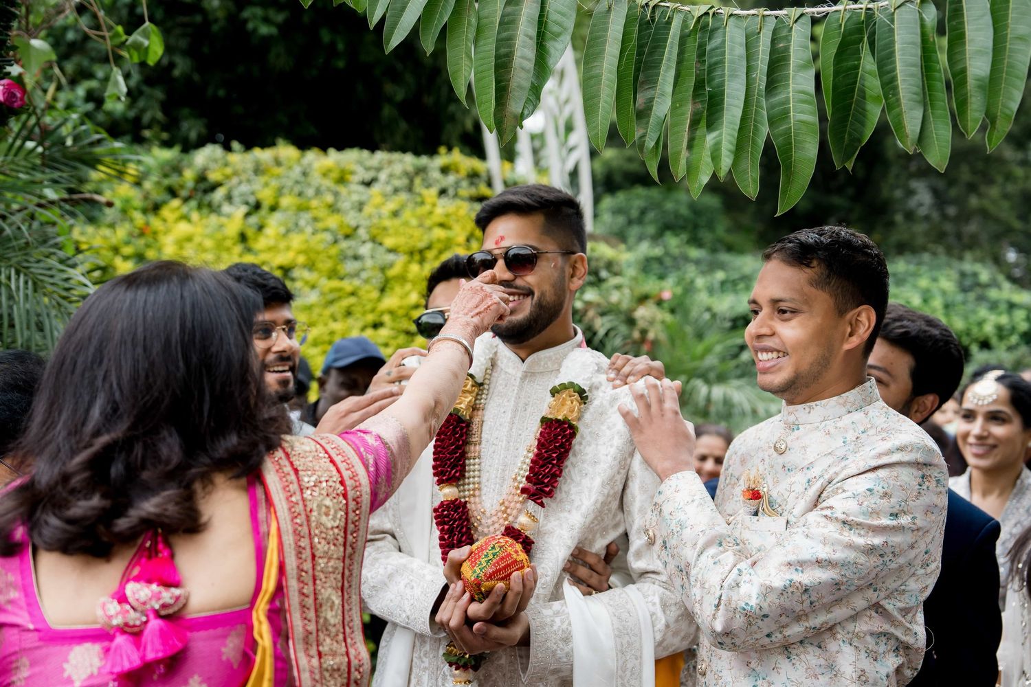 Traditional Indian wedding ceremony taking place in a lush garden setting.