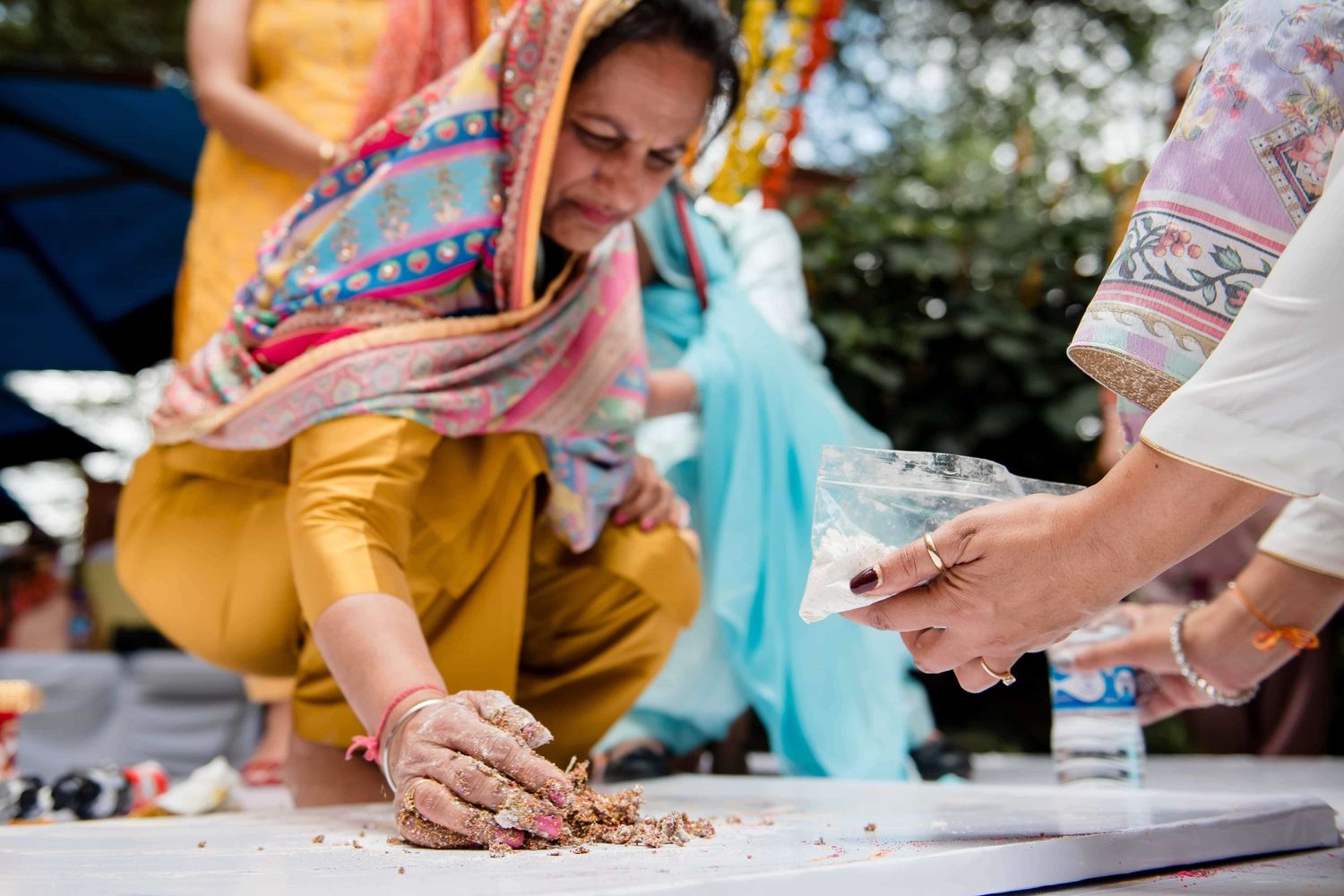 Wedding guest applying mehndi henna design during traditional ceremony.
