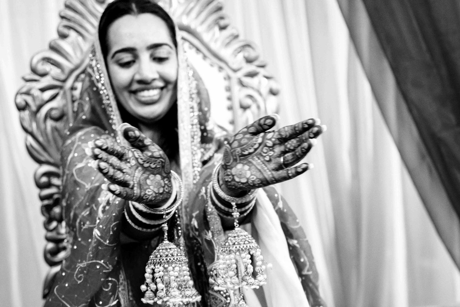 A traditional Indian bride shows off her intricately decorated henna hands during a wedding celebration.