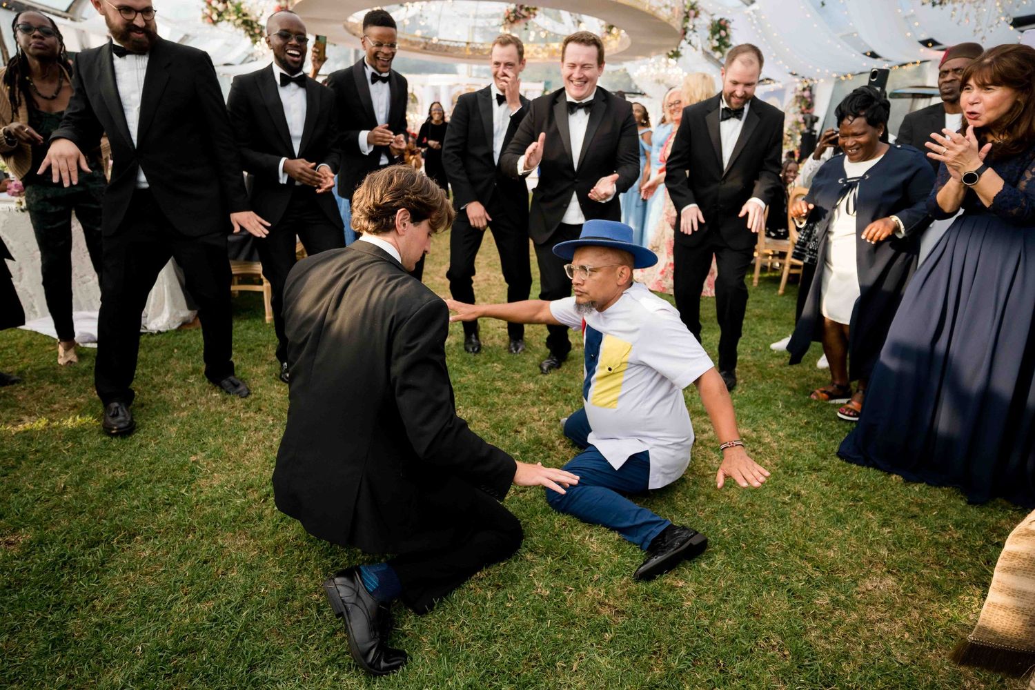 Wedding guests gather on the grass in formal attire during an outdoor celebration.