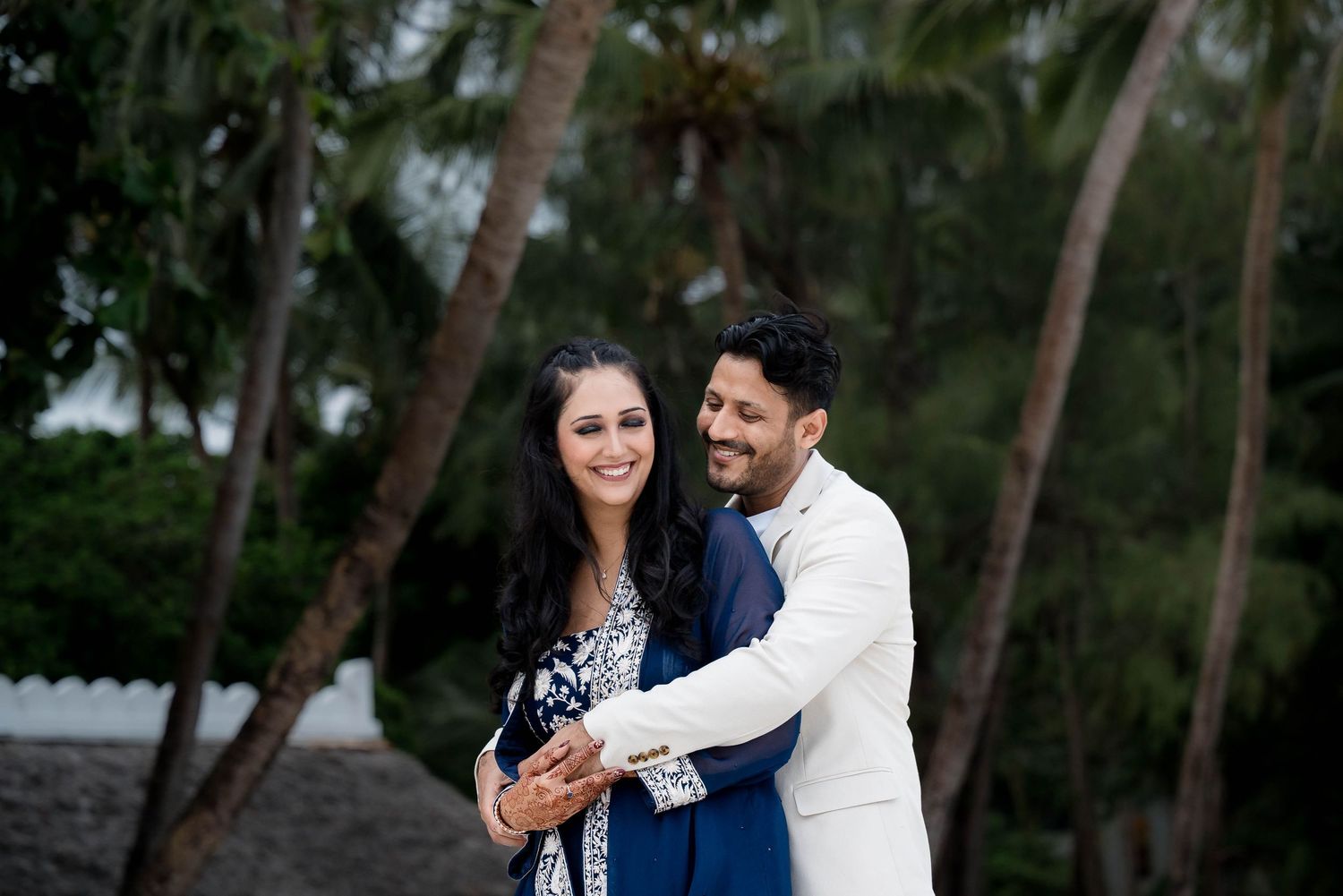 A couple shares a romantic moment together in a lush green forest setting during a photo session.