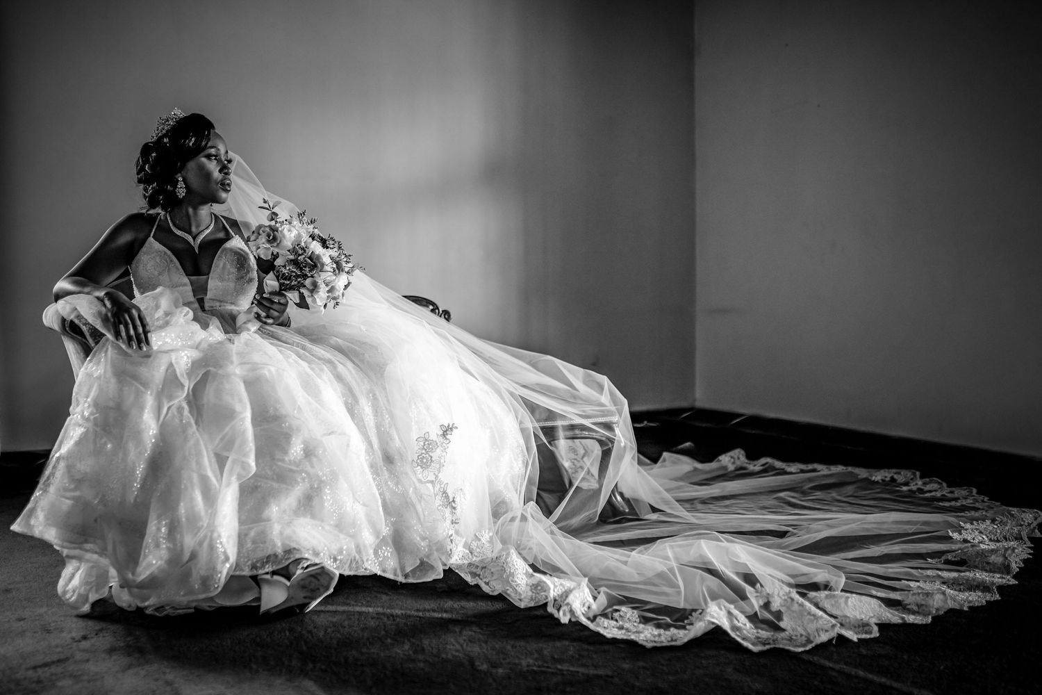 Black and white photo of a bride in an elegant flowing wedding gown with long train.
