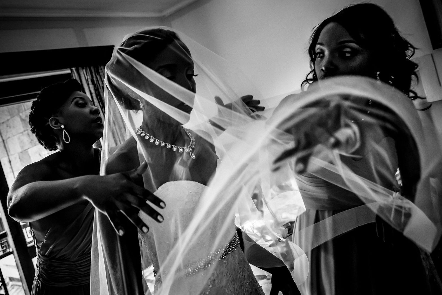 Artistic black and white composition shows wedding guests dancing and celebrating at a reception.
