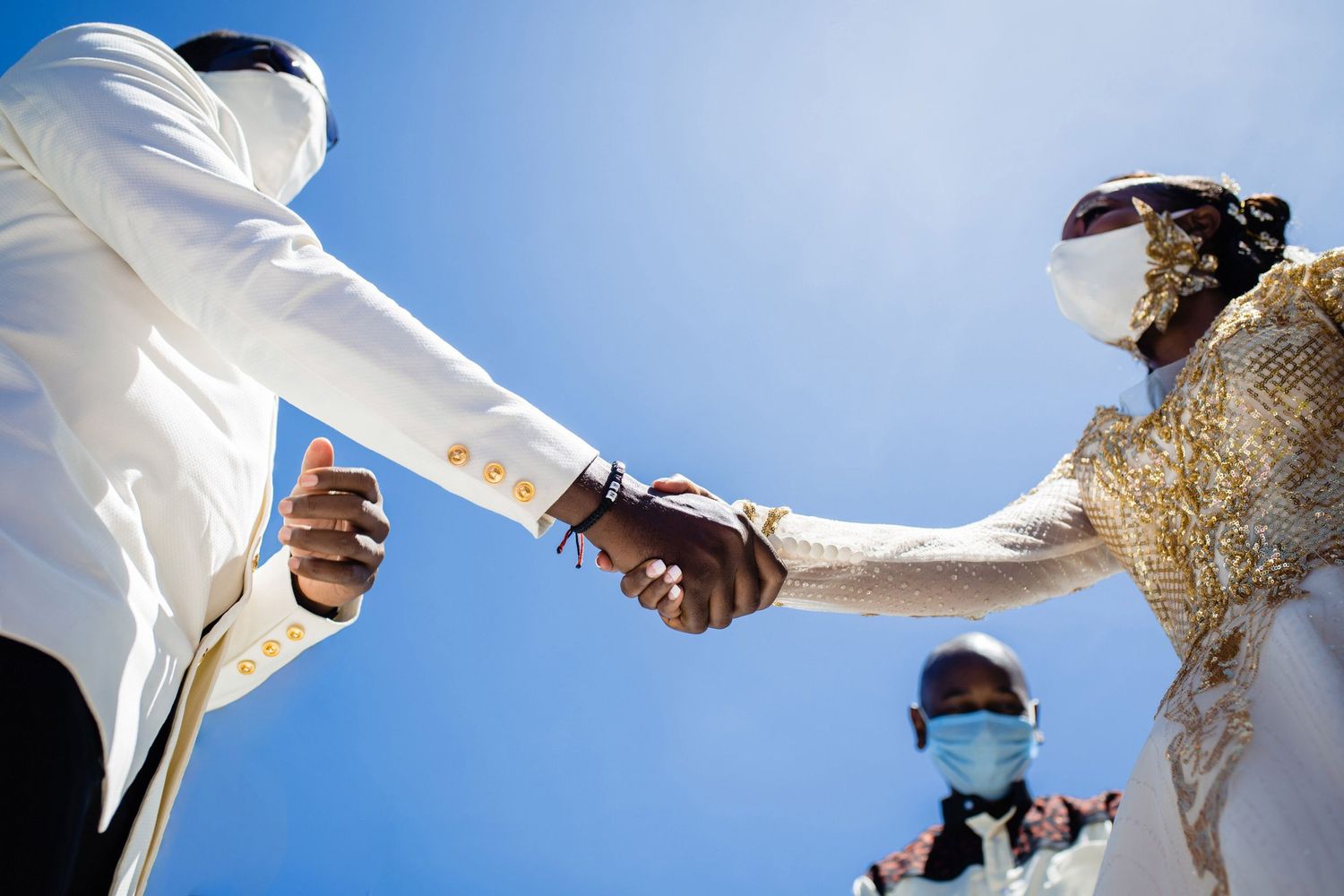 Wedding details photographed against bright blue sky with white fabric flowing in the wind.