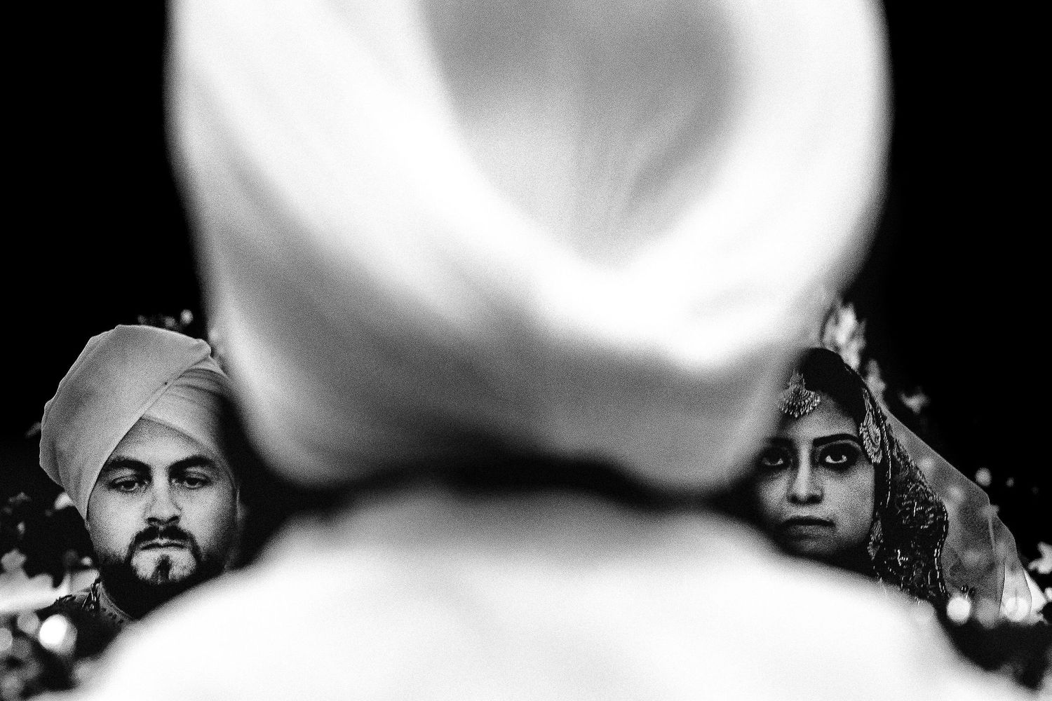 Artistic black and white photograph capturing three figures in traditional turbans.