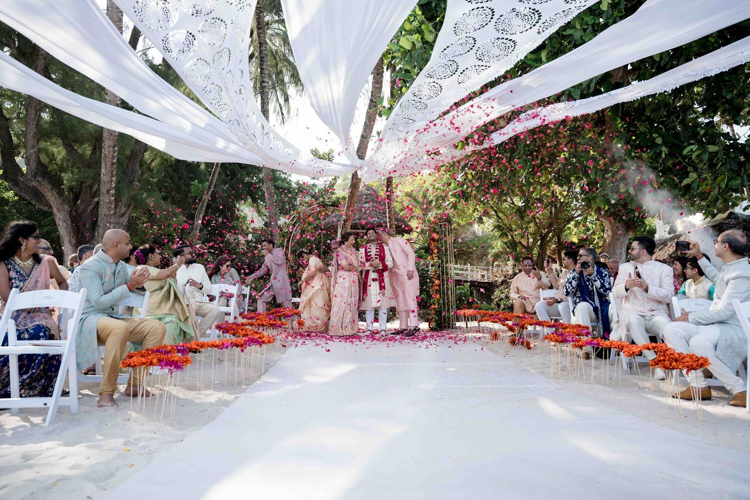 A panoramic view of an outdoor wedding ceremony setup with white fabric draping and orange floral decorations.