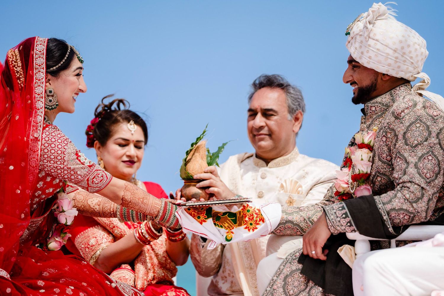 Joyful moments captured during an Indian wedding ceremony with traditional red and gold attire and decor.