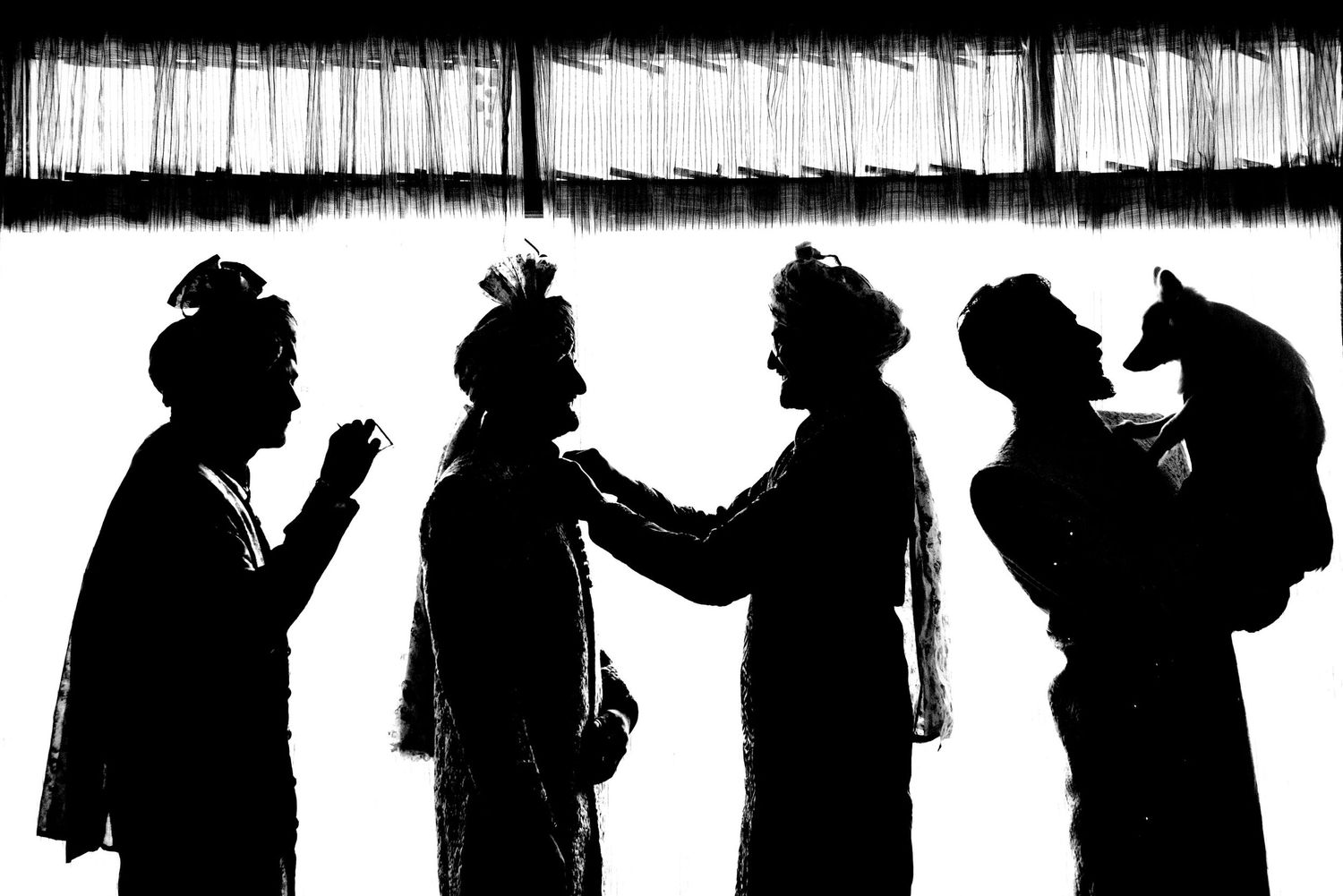 Black and white silhouette of a group interacting against a striped background.