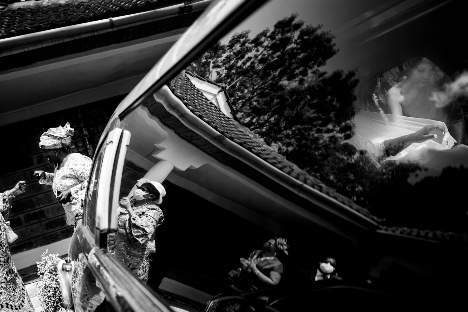 Artistic black and white photo of wedding guests looking through car windows.
