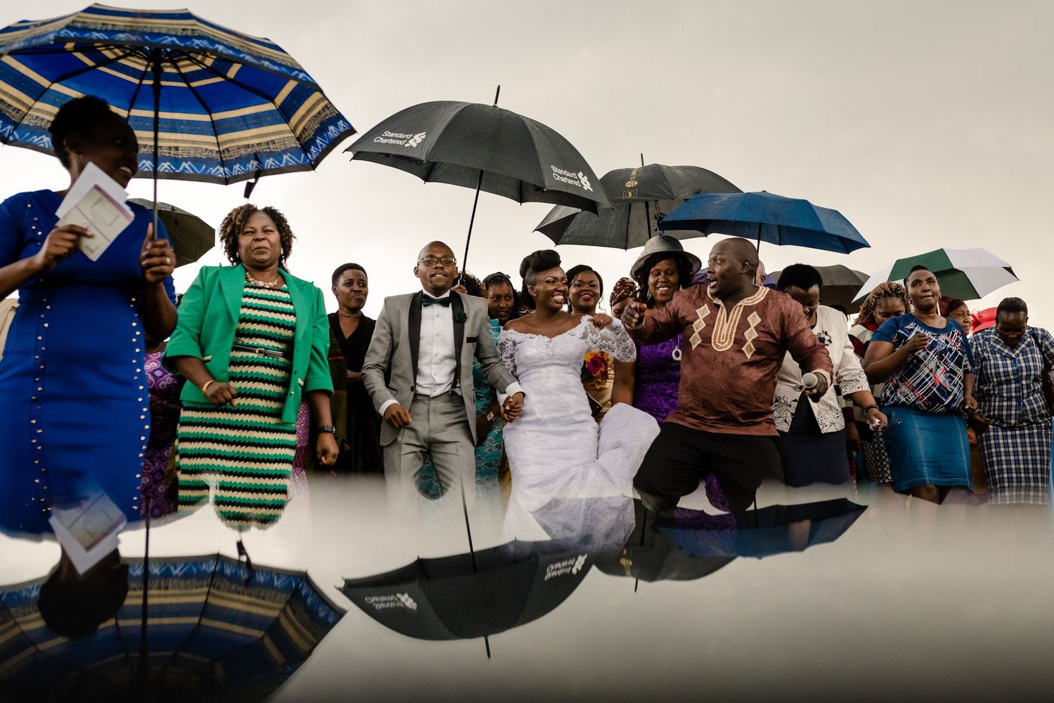 Row of people holding colorful umbrellas against an overcast sky.