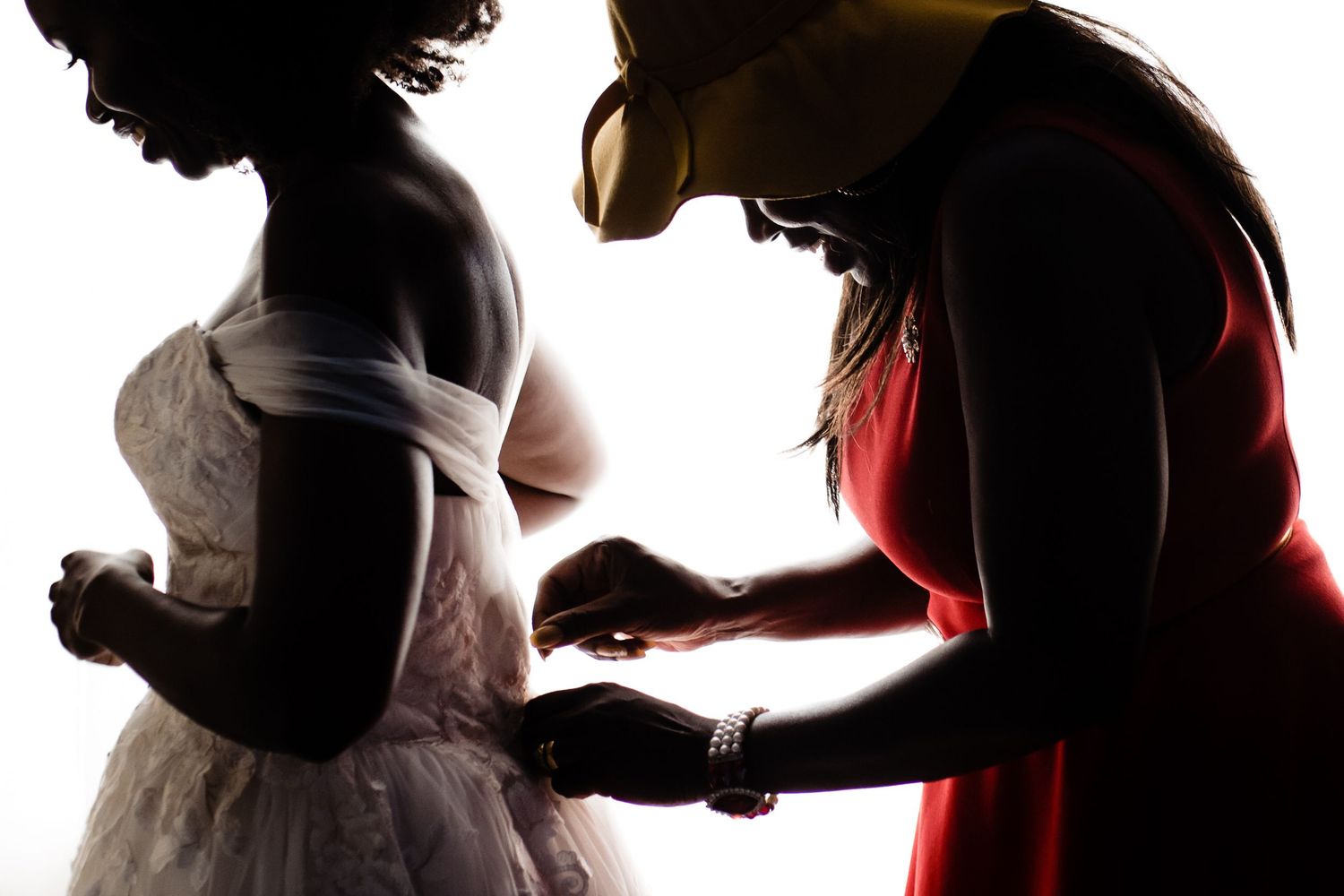 Dramatic silhouettes of a wedding couple in profile against bright white background.