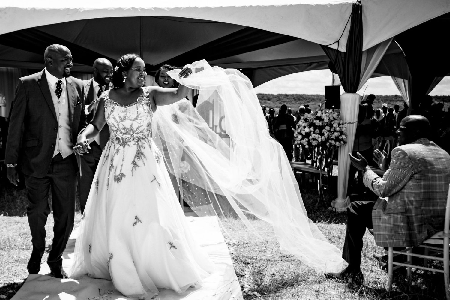 Black and white image of people celebrating at an outdoor event with flowing white fabric.