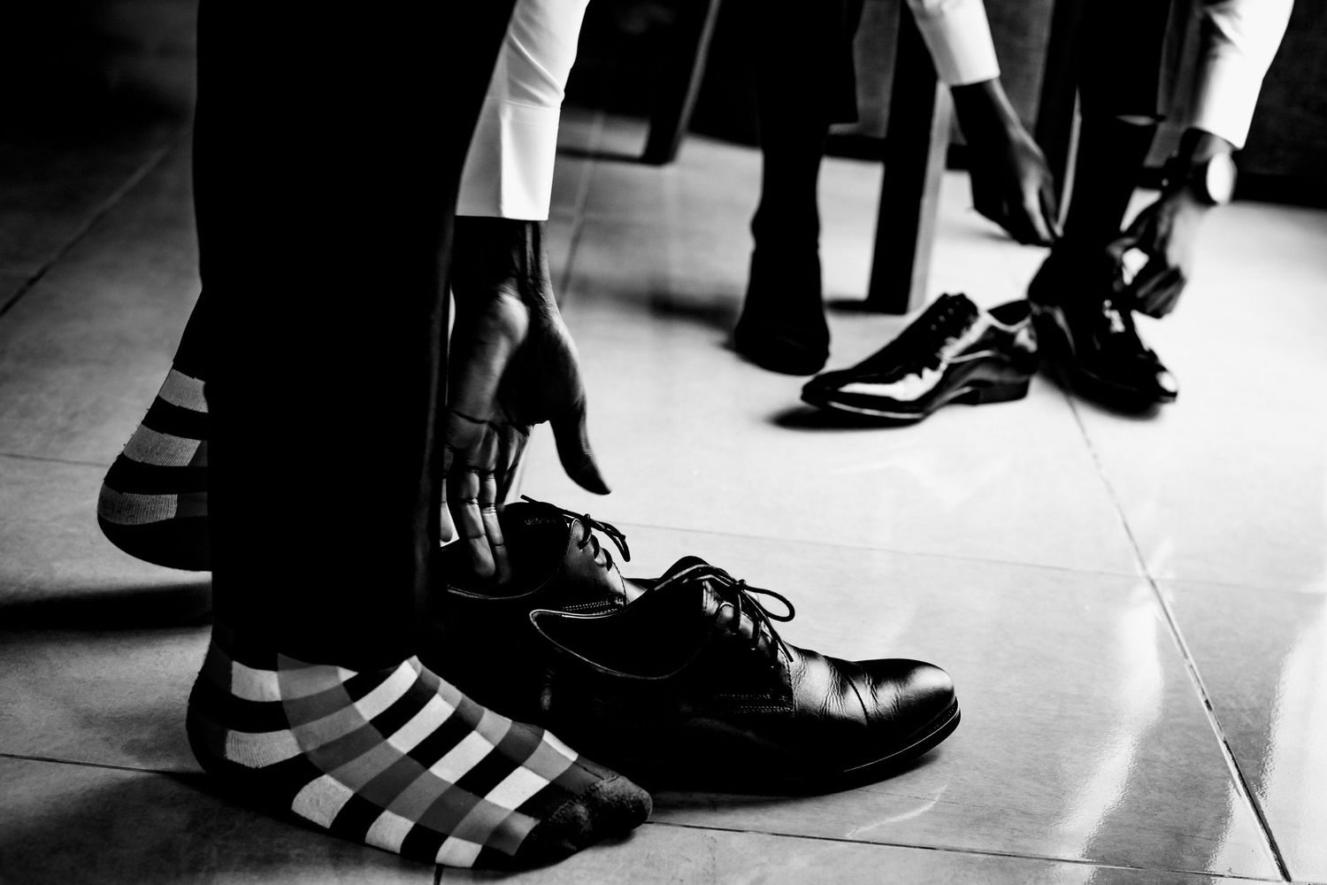Black and white image of feet wearing dress shoes and casual sneakers.
