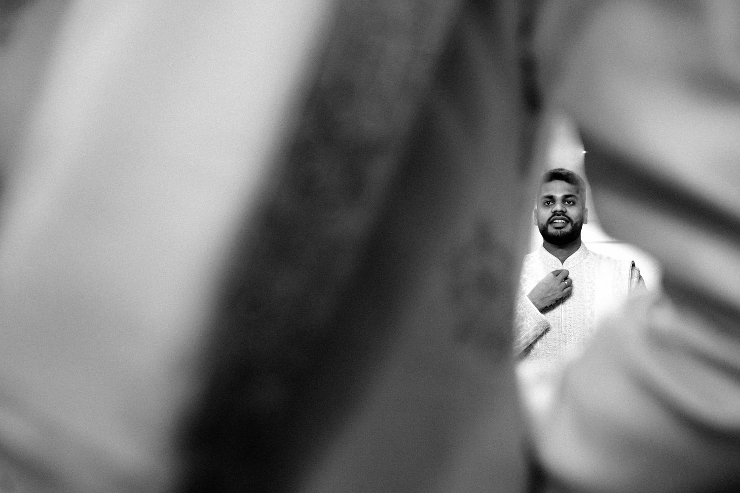 Artistic black and white portrait shot with selective focus and blurred elements.
