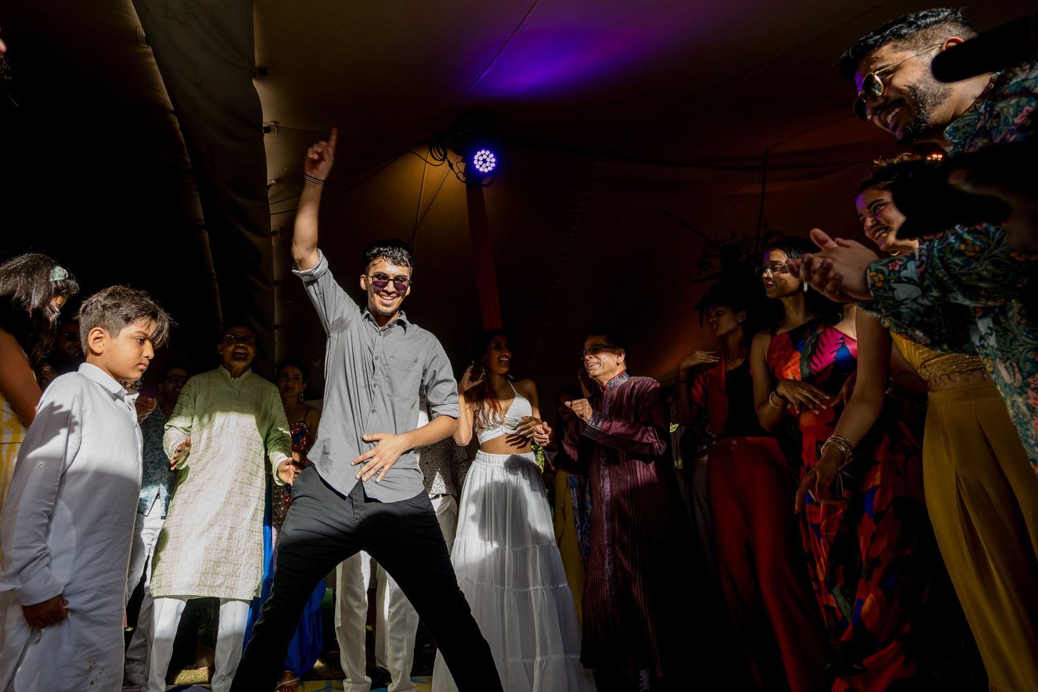 Dance party scene with guests celebrating under dramatic purple lighting.