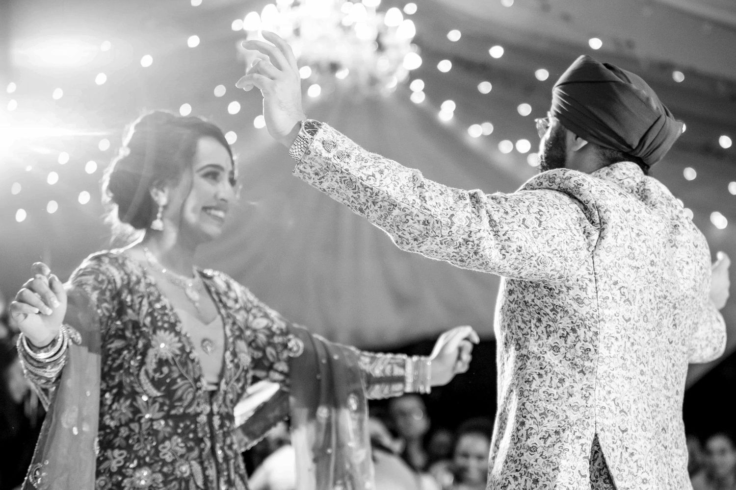 A couple dances together under twinkling lights at their reception celebration.
