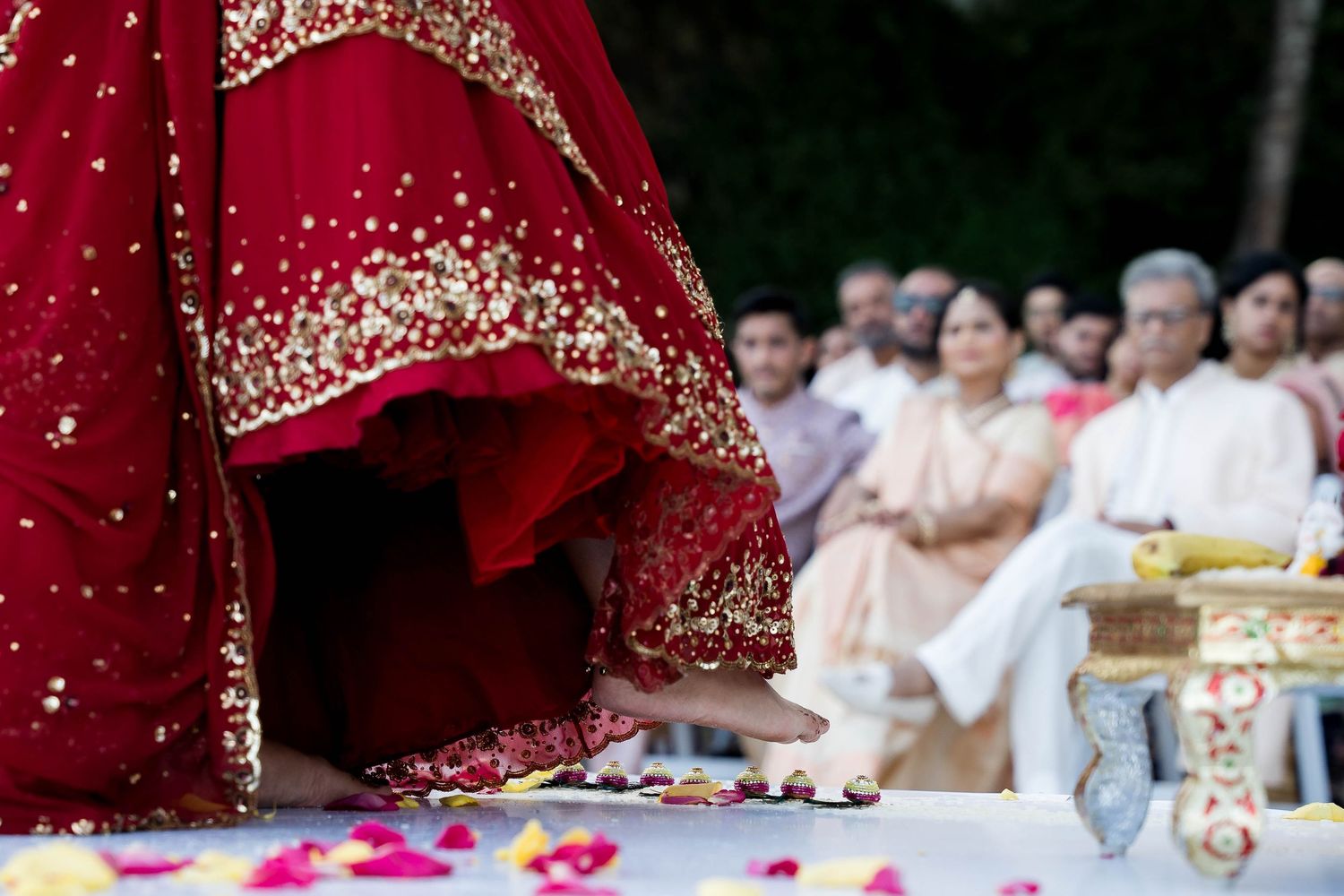 A traditional Indian wedding ceremony with red and gold decor showing guests seated during the rituals.
