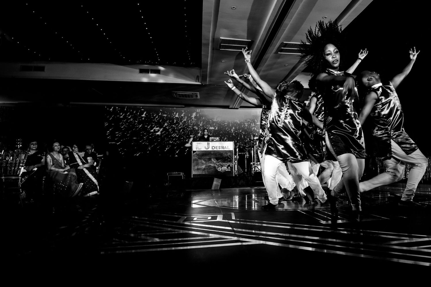 Silhouettes of people dancing and celebrating in a dark venue.