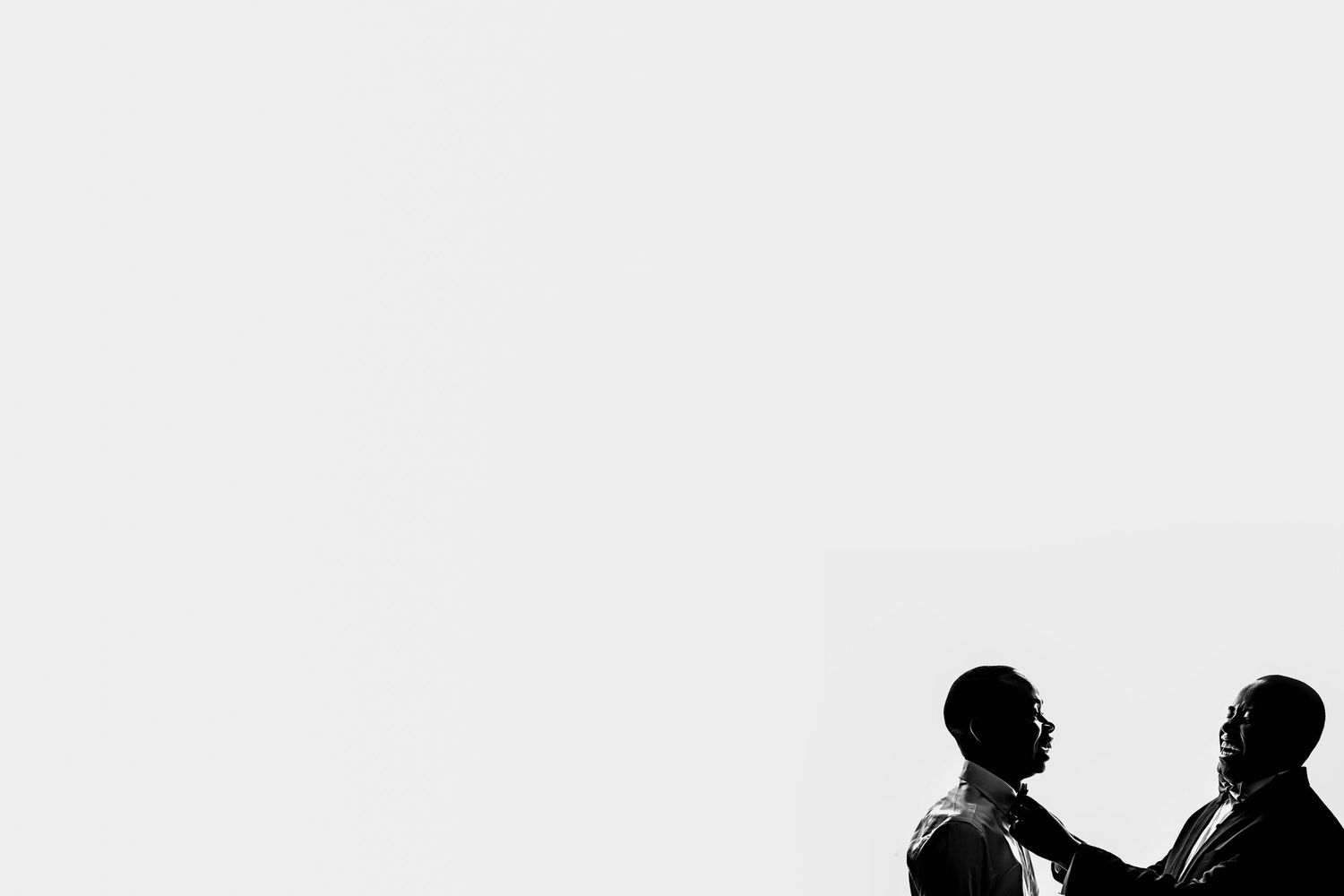 A minimalist black and white silhouette of two figures against a white background.