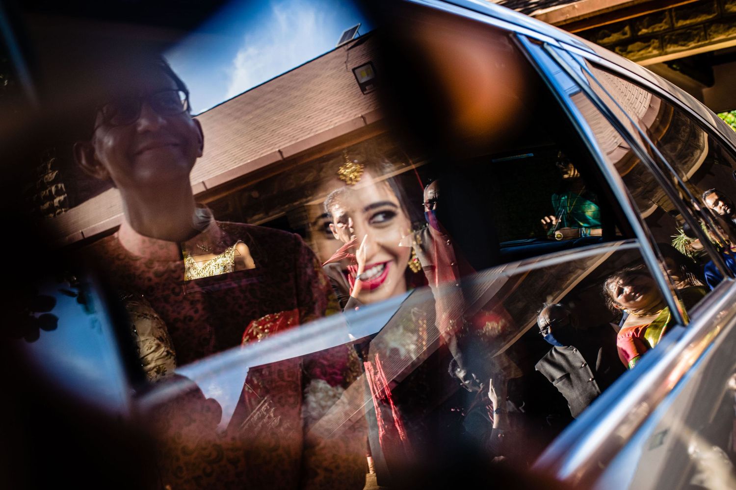 Wedding guests looking through car window during celebration.