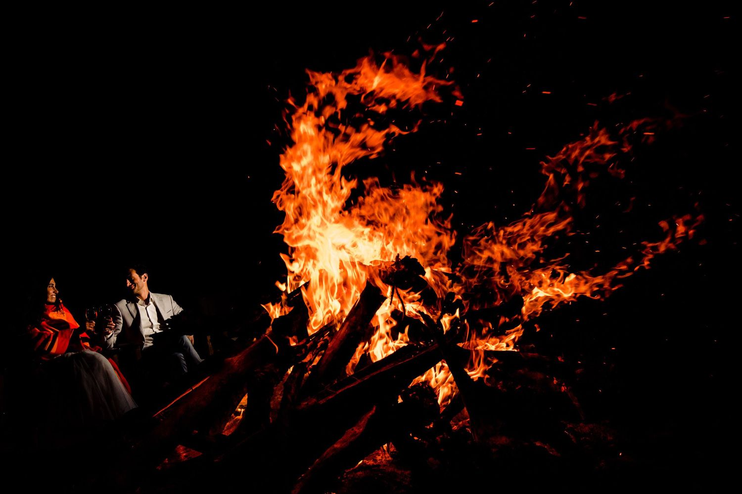 Large bonfire flames illuminating dark night scene.