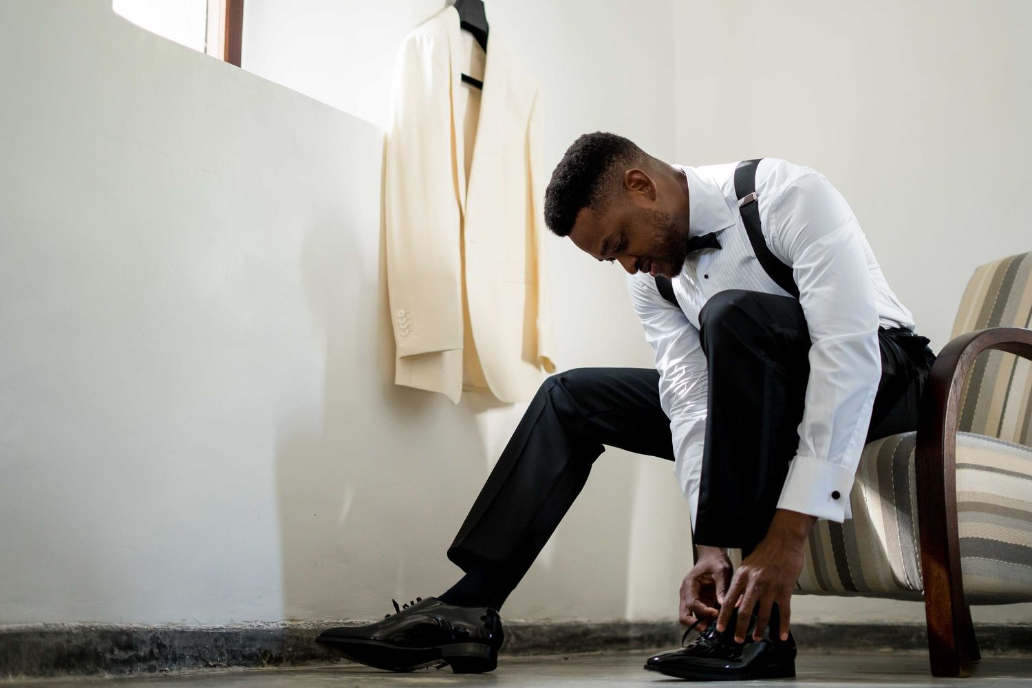A series of black and white photographs showing someone in formal attire sitting and moving in different poses against a wall.