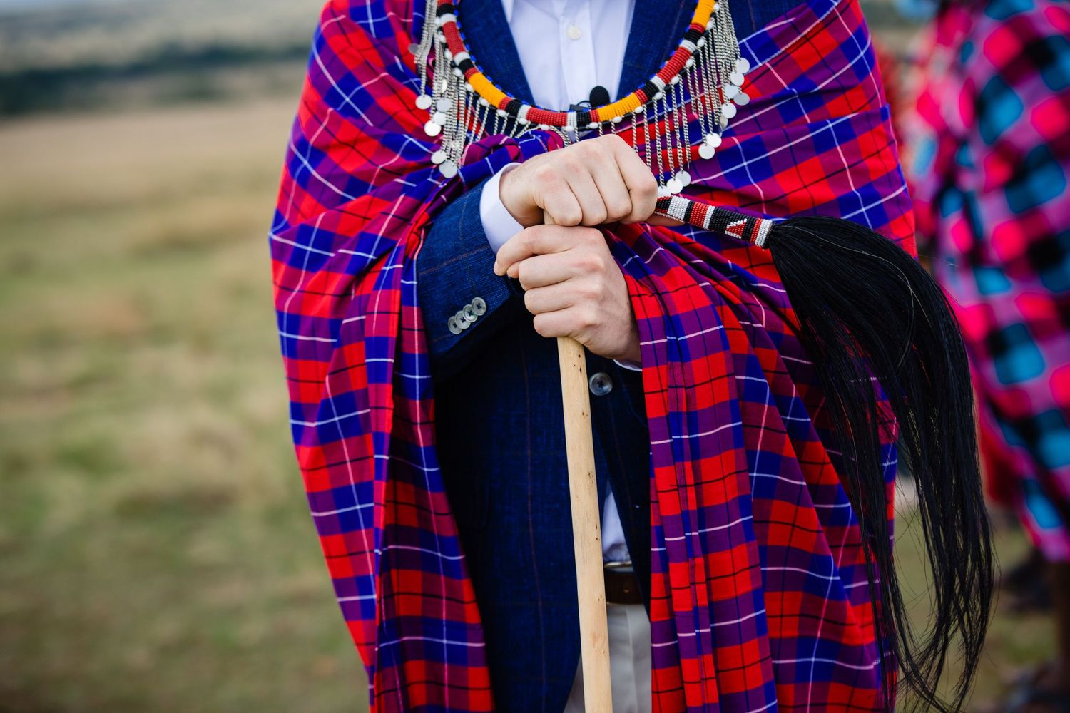 Close-up details of red and blue plaid traditional Maasai clothing and decorative beadwork.
