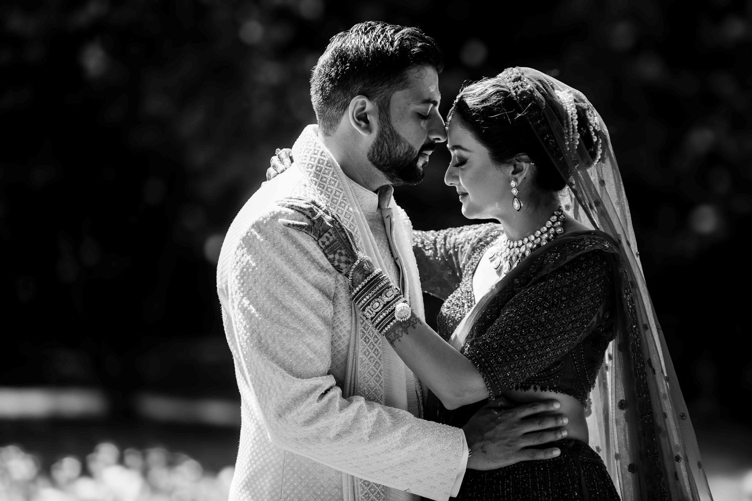 A romantic black and white portrait of a couple in traditional wedding attire.