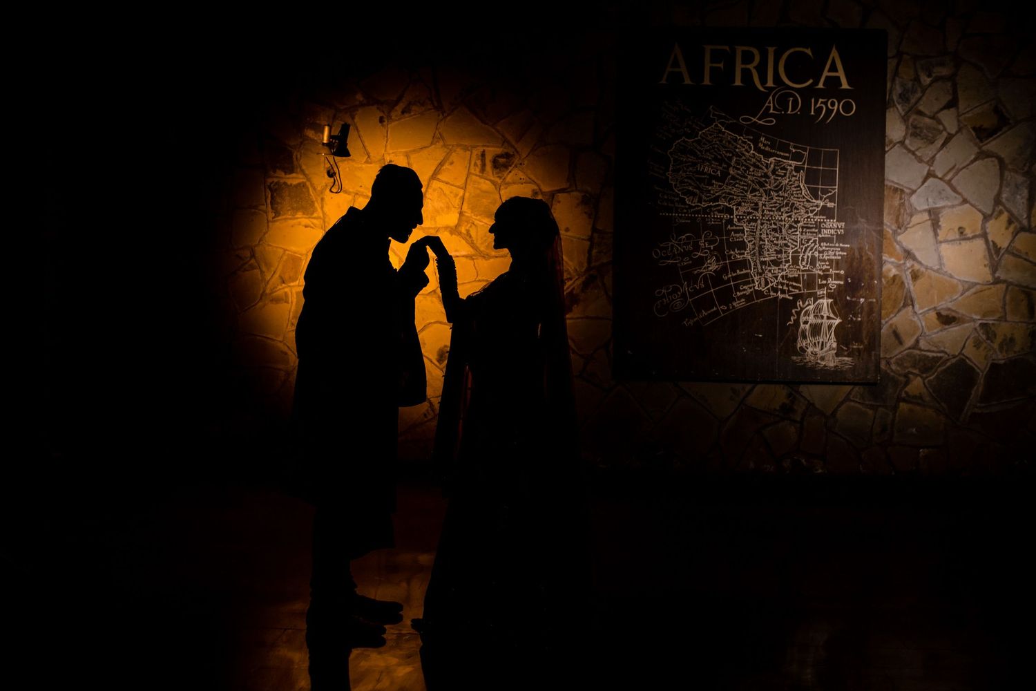 Dramatic silhouette of two figures against an orange-lit wall with Africa text visible.