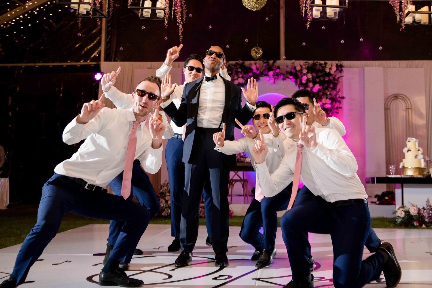 Groomsmen strike playful poses on the dance floor at a wedding reception.