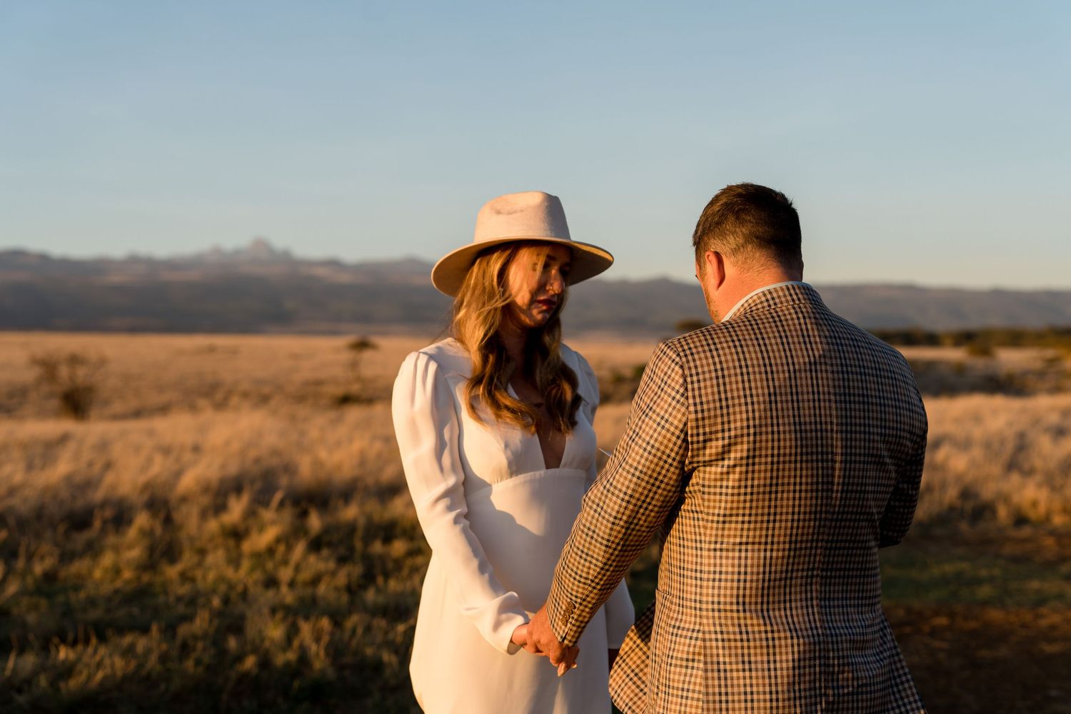 A couple shares a tender moment against a desert mountain backdrop at sunset.