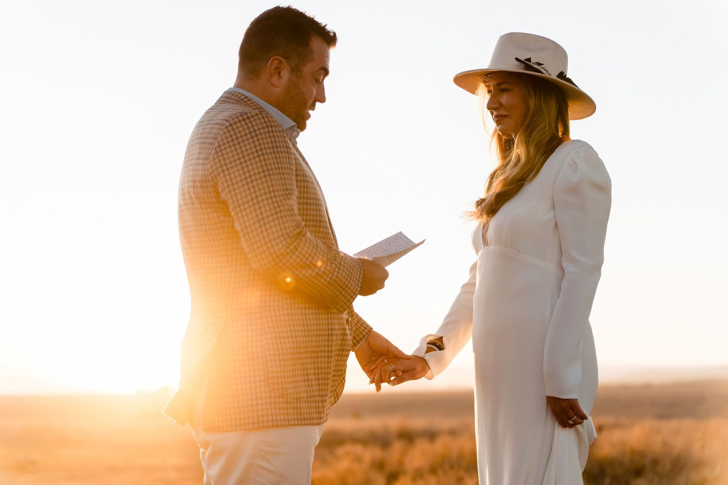 A couple exchanging vows during a sunset ceremony in a desert setting.