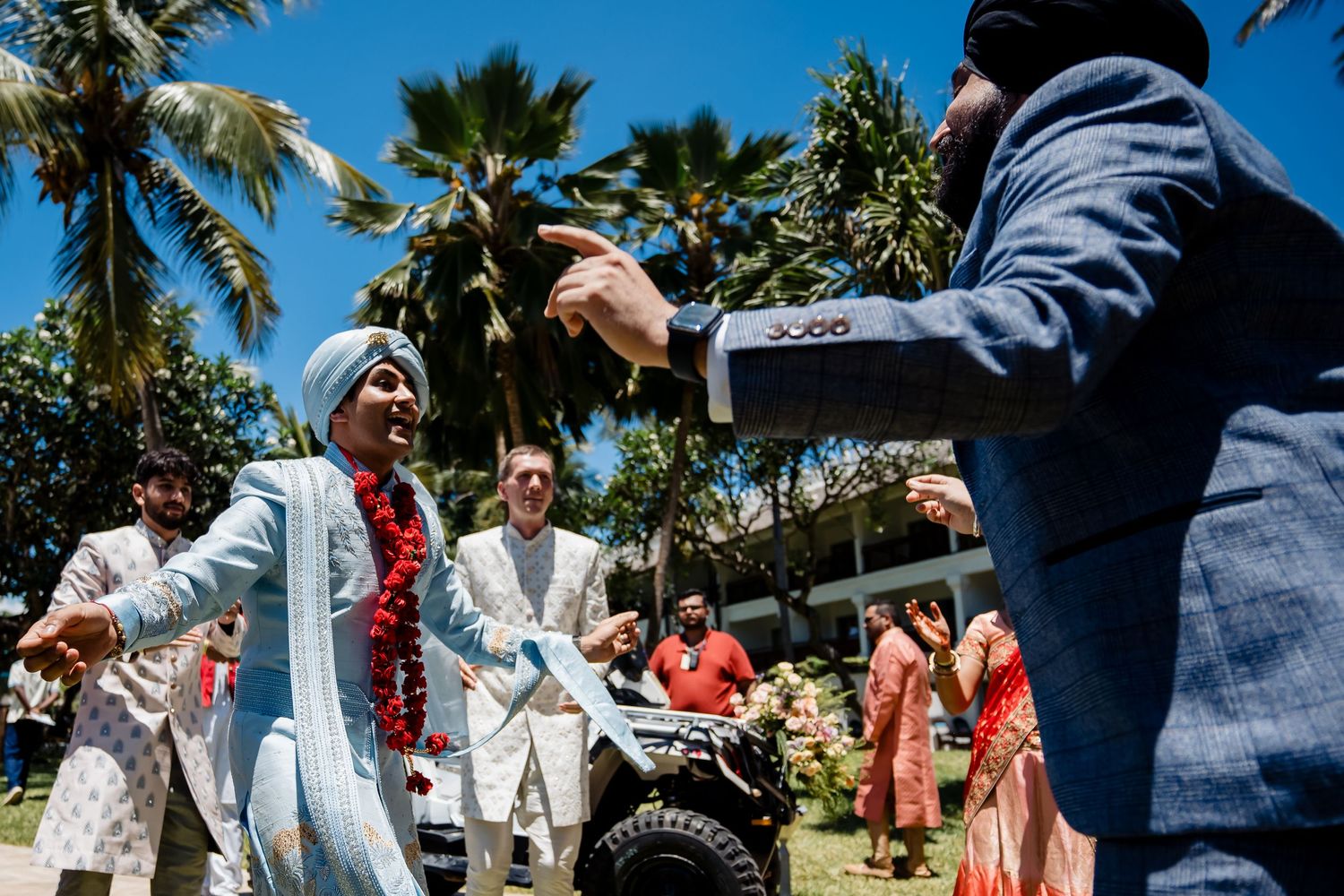Festive celebration with people dancing and enjoying music under swaying palm trees.