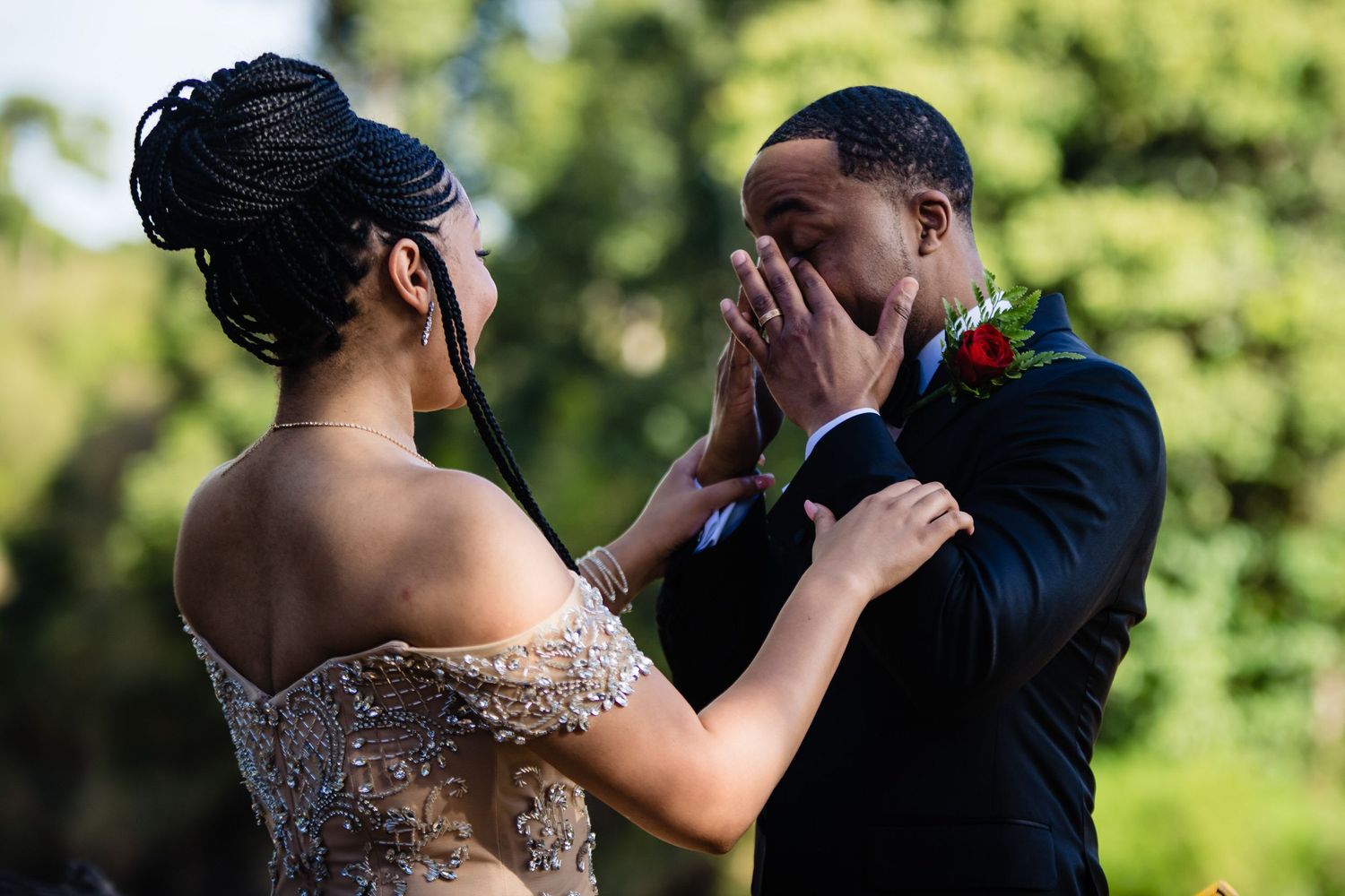 A couple shares an intimate dance moment in a sunny garden setting.