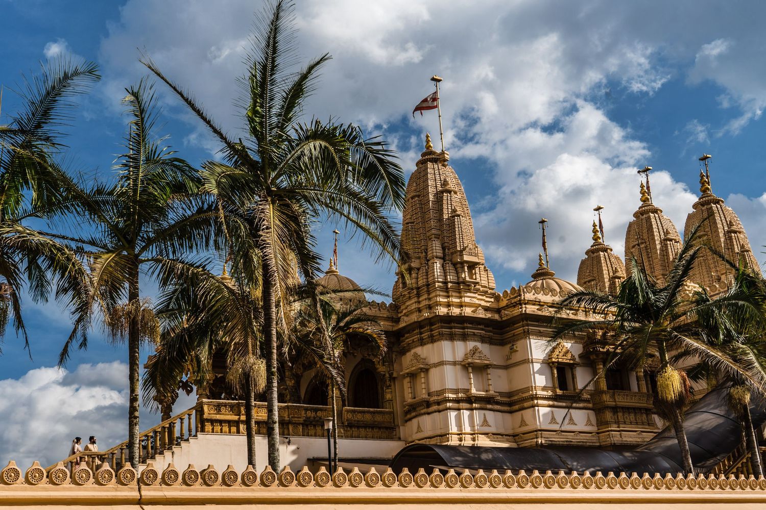 Ornate temple spires and palm trees against a blue sky with white clouds.