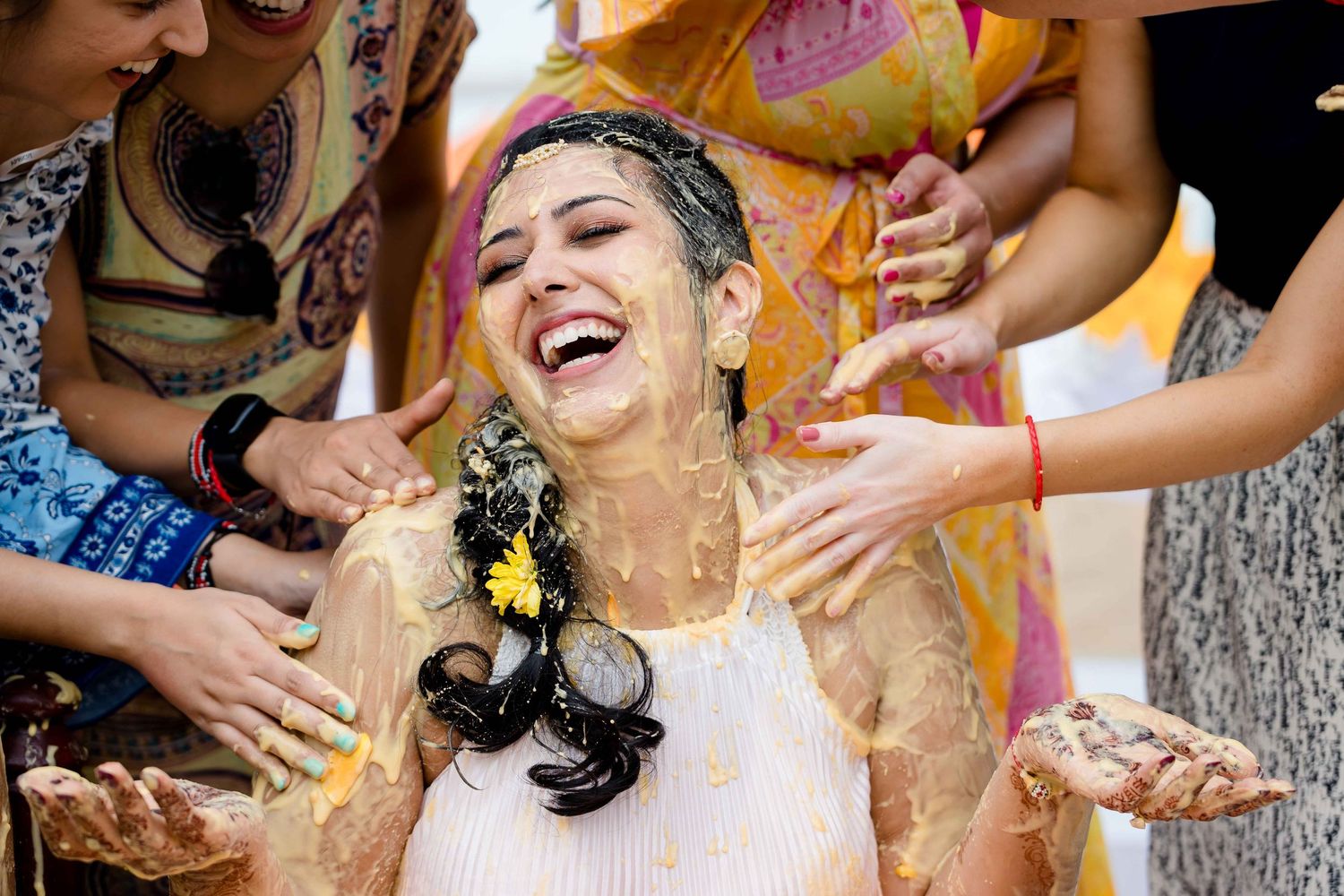 A joyful celebration scene with people throwing colorful powder and having fun at a Holi festival event.