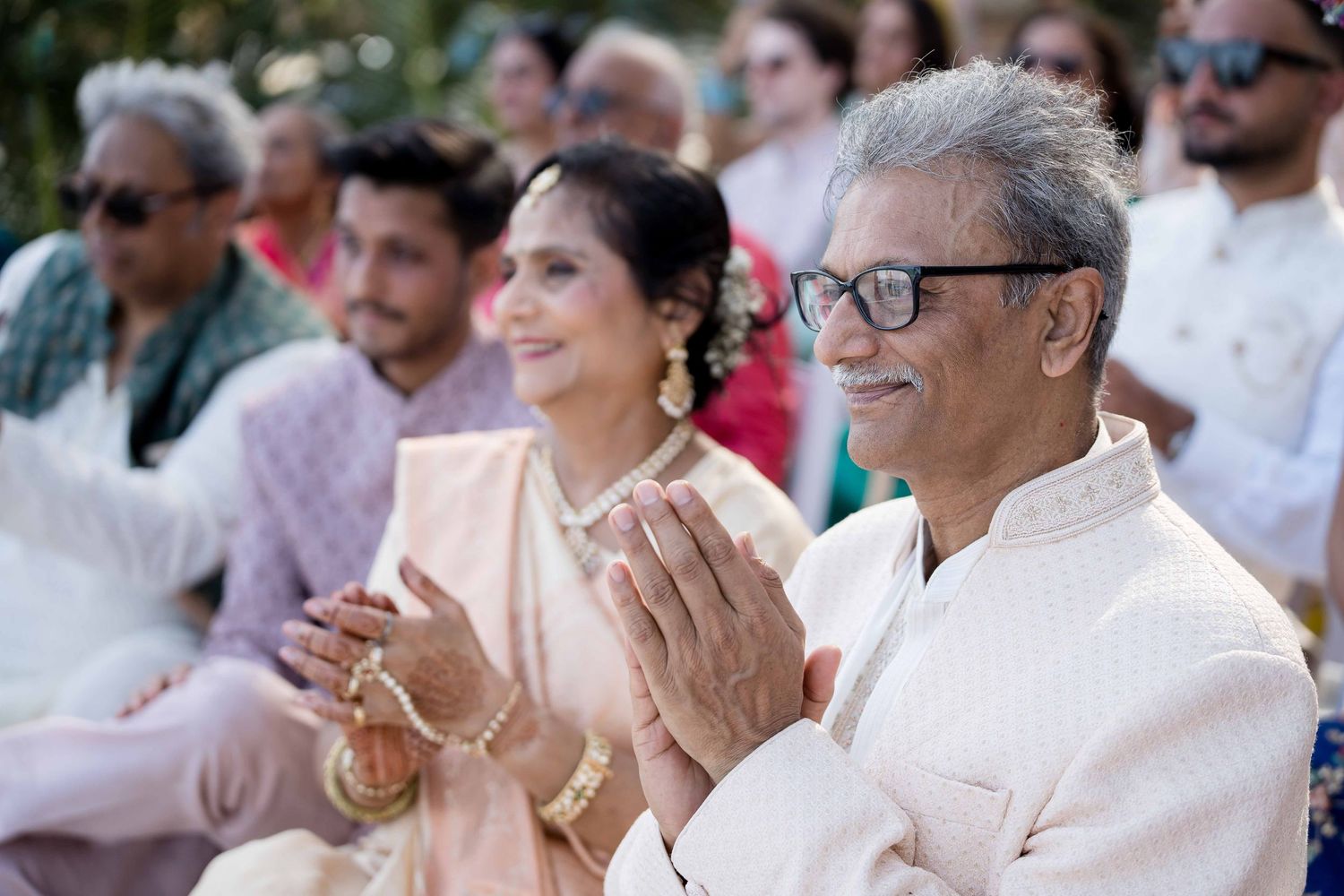 Audience members smile and laugh while seated outdoors during a daytime event.