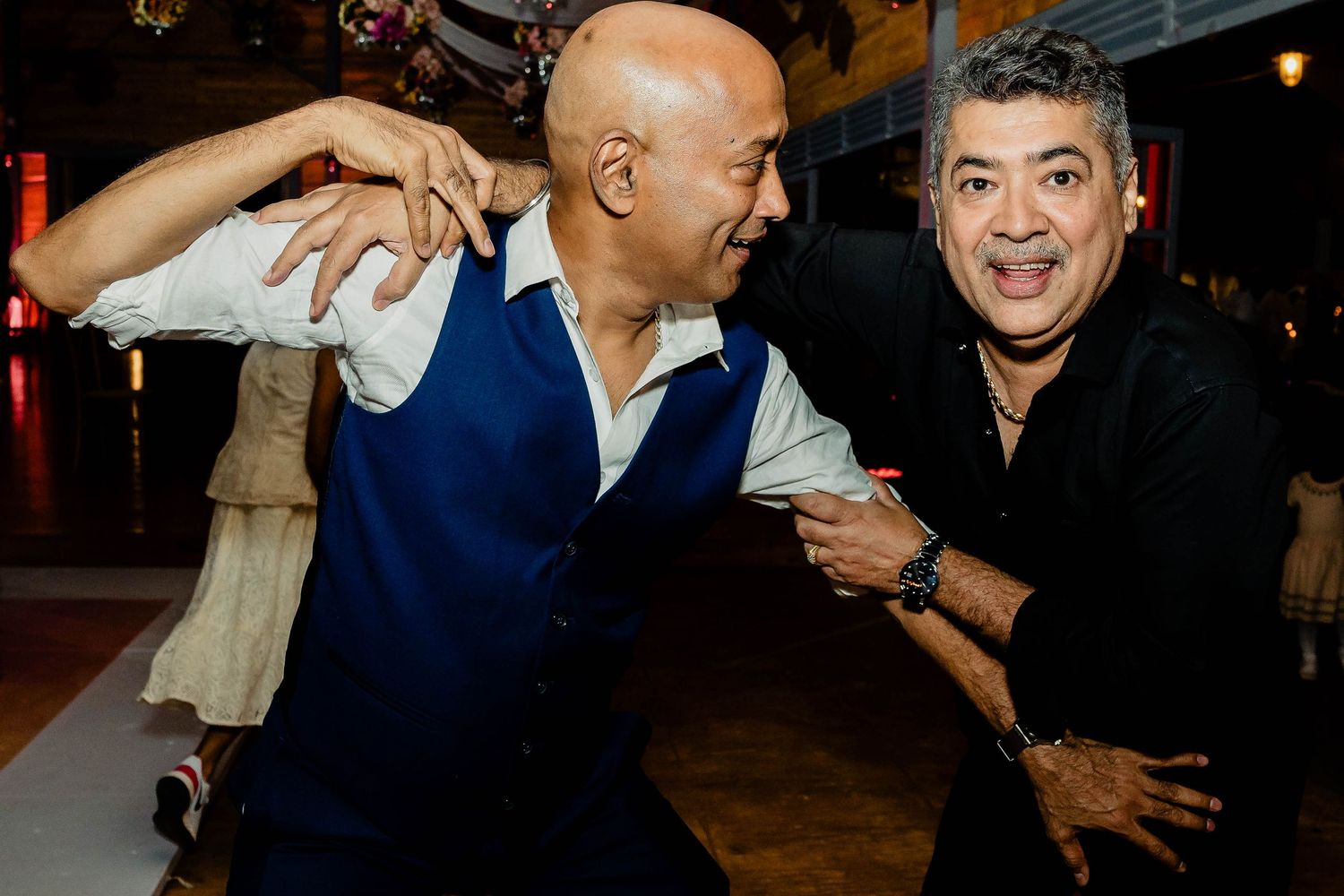 Two guests share a lively moment dancing at a wedding reception.
