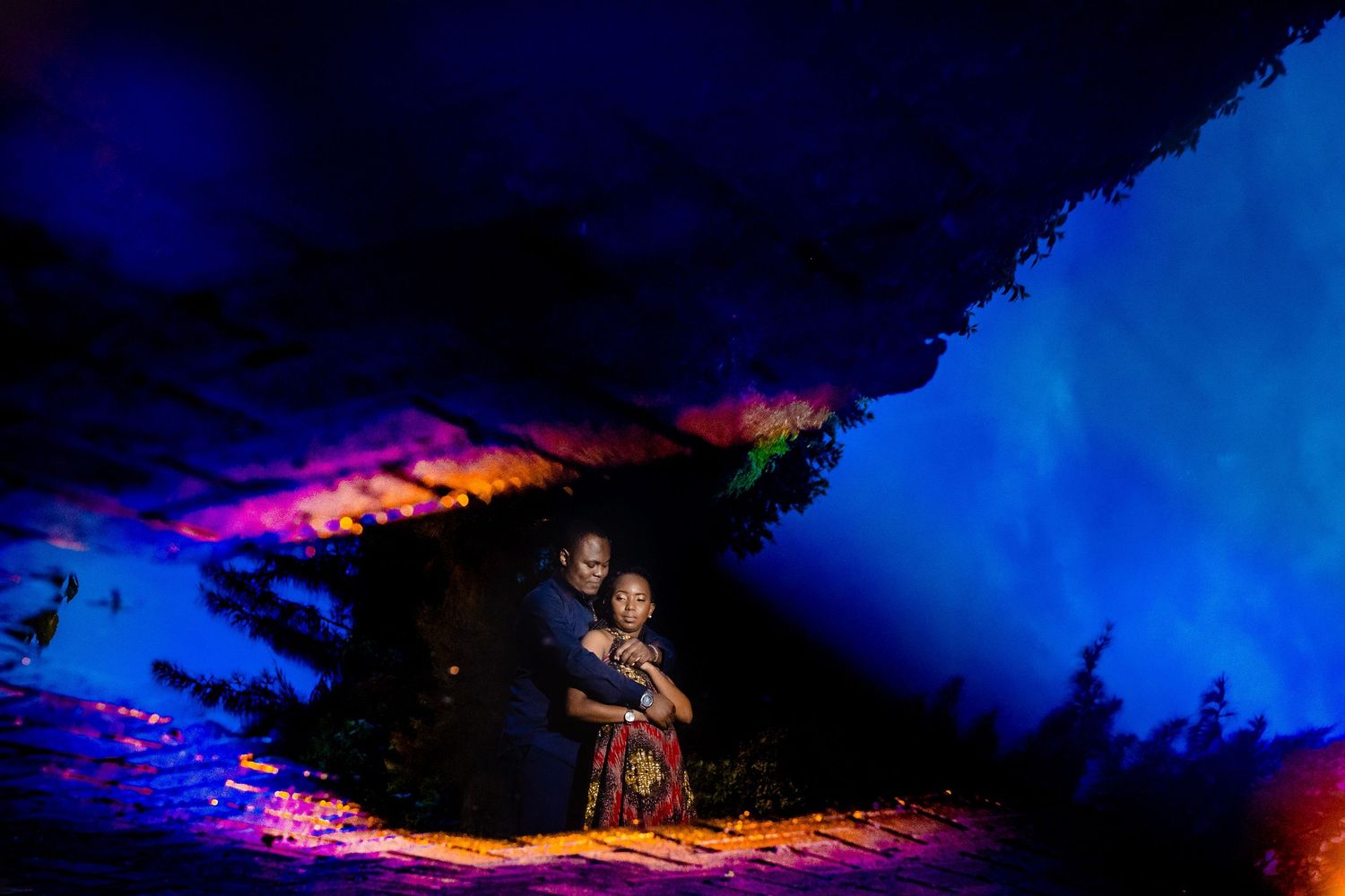 Dramatic nighttime landscape with deep blue lighting and pink accents.
