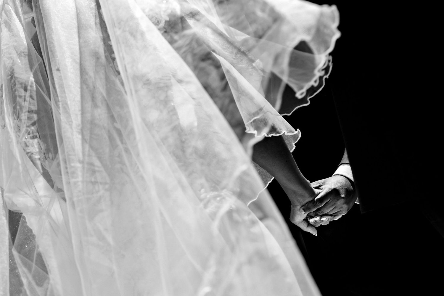 Close-up details of flowing white wedding veil against dark background.