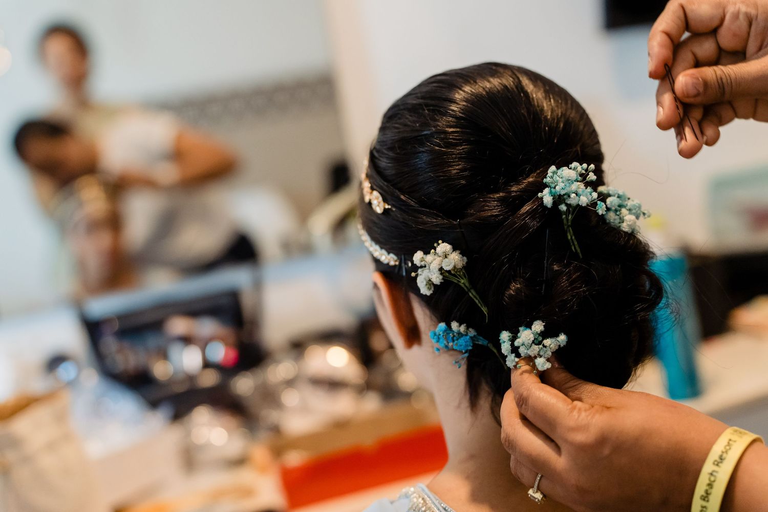 Close-up of bridal hair styling with delicate white flowers being placed in updo.