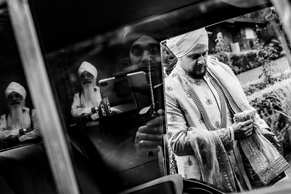 Black and white candid photograph showing traditional Sikh ceremony preparations.