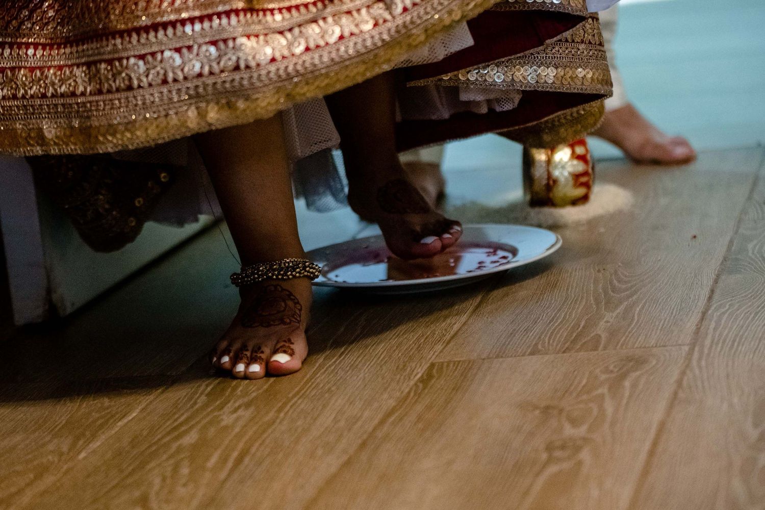 Detail shot of traditional Indian wedding attire and decorative elements on wooden floor.